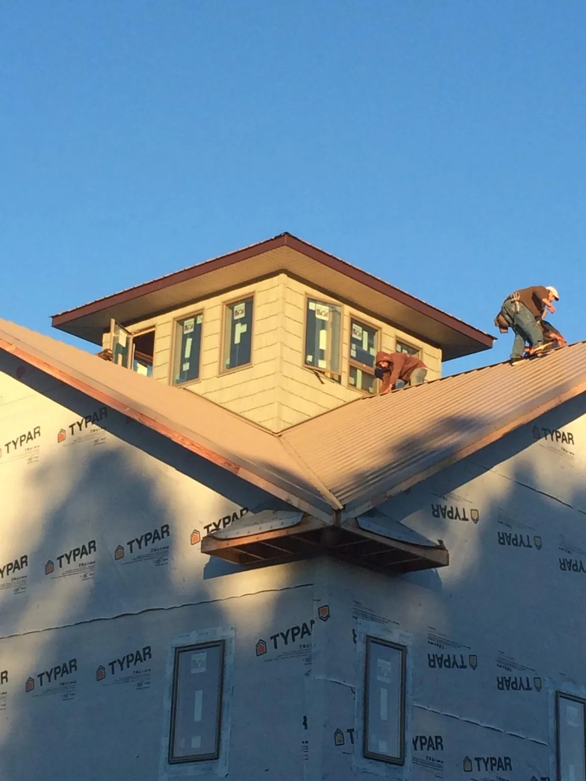 Roofers working around a rooftop cupola on a new metal roof at sunset — Roof Waterproofing in Mineral Springs by Roofing Brothers